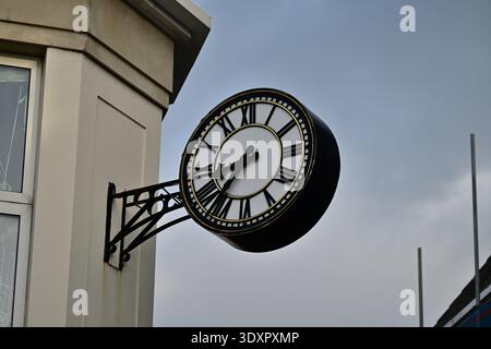 Orologio da strada ornato a due lati sulla facciata dell'edificio storico Foto Stock