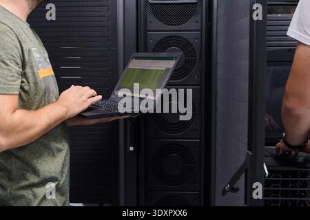 Tecnico IT che utilizza un laptop nella sala server per la gestione delle apparecchiature di rete in un ambiente di data center Foto Stock