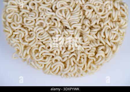 Il disco per spaghetti istantanei crudi con struttura riccia dettagliata, sfondo neutro e profondità di campo ridotta accentuano i filamenti di amido, utili per l'ingrossamento Foto Stock