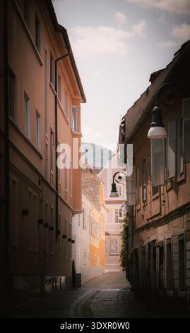 Affascinante strada stretta in una storica città vecchia europea con edifici dai colori pastello e luce soffusa del sole. Tranquillo vicolo acciottolato. Foto Stock