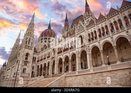 L'edificio del Parlamento ungherese si erge in modo prominente sotto un drammatico cielo al tramonto Foto Stock