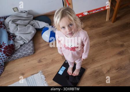 Carina ragazza caucasica di 4 anni in piedi su bilance Foto Stock