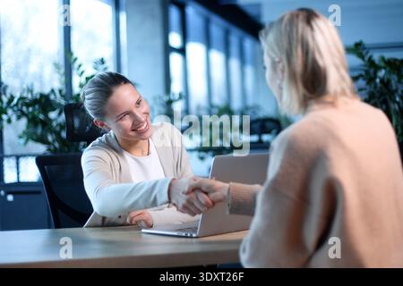 Due donne che stringono la mano in una riunione d'affari Foto Stock
