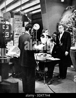 Questa foto promozionale del 1952 cattura Dave Garroway, il presentatore originale dello spettacolo Today della NBC, in un vivace ambiente da studio. Circondato da personale di produzione e attrezzature, Garroway (all'estrema destra, in smoking) sta in piedi mentre un membro della troupe indossa cuffie e altri lavora alla scrivania, illustrando l'energia dal vivo e caotica delle prime trasmissioni televisive. Foto Stock