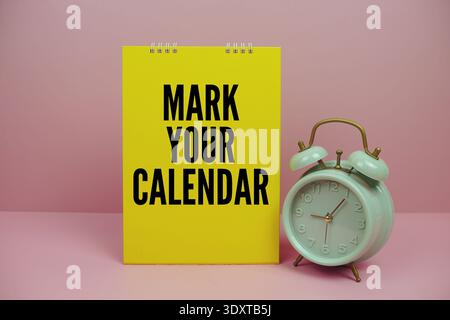 Messaggio motivazionale "segna il tuo calendario" con sveglia verde vintage, su sfondo rosa Foto Stock