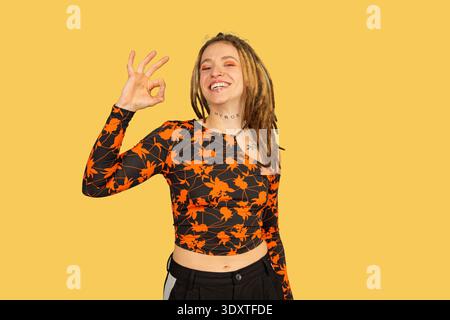 Giovane donna con dreadlock, tatuaggi e piercing, sorridente, che ritrae fiducia e approvazione Foto Stock