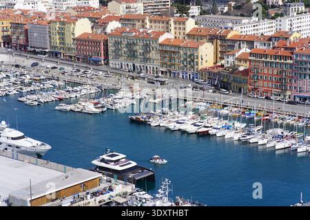 Vista panoramica aerea dello storico porto di Nizza con acque blu profonde, yacht di lusso ormeggiati saldamente e facciate vivaci e colorate. Foto Stock