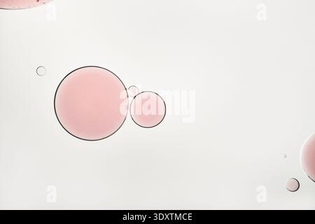 Gocce di olio rosa che galleggiano nell'acqua formando uno sfondo liquido astratto Foto Stock