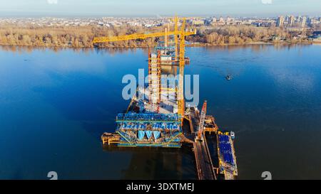 Veduta aerea di un vivace cantiere sull'acqua con una gru torreggiante e la struttura in via di sviluppo, Novi Sad, Vojvodina, Serbia. Foto Stock