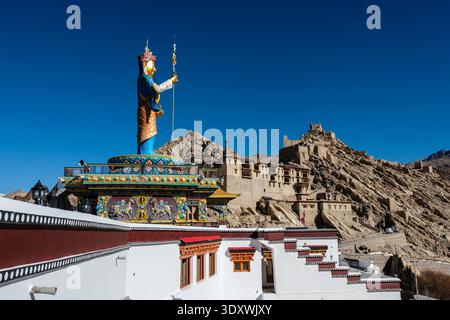 Un profilo laterale della colorata statua di Guru Padmasambhava si affaccia sulle storiche mura di pietra del Palazzo Shey, costruito nell'aspra montagna. Foto Stock