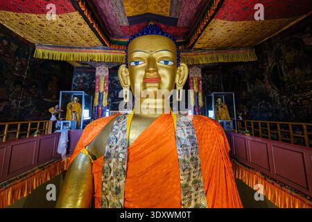 La faccia serena della statua di Shakyamuni Buddha dorata in rame domina l'interno ornato del tempio di Shey. Foto Stock