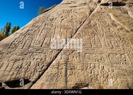 Antiche incisioni rupestri di cinque Buddha a Shey incise in un grande masso naturale che mostra dettagliate iconografie e figure religiose. Foto Stock