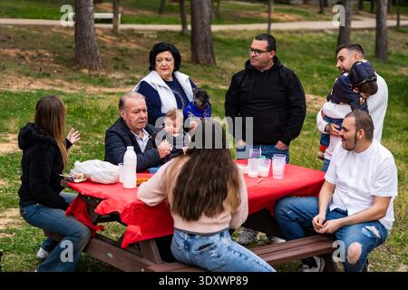 Famiglie di generazioni diverse che si riuniscono all'aperto attorno a un tavolo da picnic Foto Stock