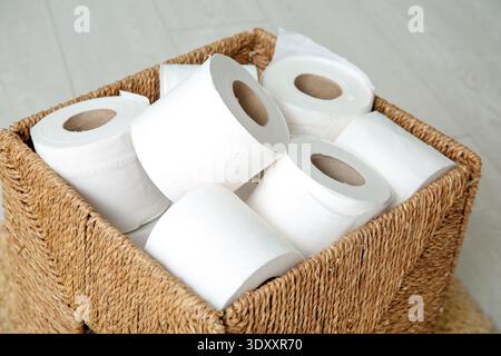 Cestino in vimini con rotoli di carta igienica sul pavimento, primo piano Foto Stock