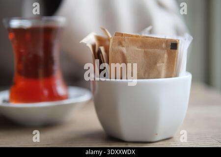 Tè servito con pacchetti di zucchero in un ambiente da caffe' Foto Stock