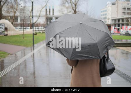 Camminare con un ombrello in una giornata di pioggia in città Foto Stock