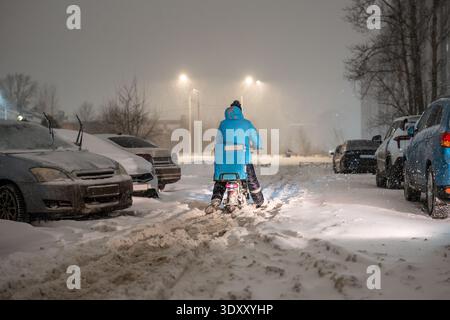 Il trasporto crollerà in città durante la tempesta di neve, persona che effettua la consegna in bicicletta camminando attraverso la neve. Foto Stock
