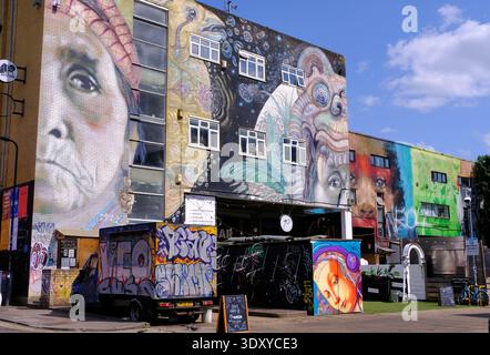 Hackney Wick: Murales colorati (Street art) su Mainyard Studios e ristoranti bar edifici, Wallis Road, River Lee, Londra, Inghilterra, REGNO UNITO Foto Stock