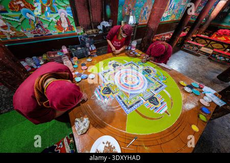 Una vista ad alto angolo mostra diversi monaci che sistemano meticolosamente un grande e colorato mandala di sabbia su una piattaforma rialzata a Hemis Gompa. Distretto di Leh Union T Foto Stock