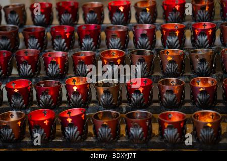 candele in detentori votivi con croci tagliate in una chiesa religiosa che significano un tributo ai morti e morenti quelli che sono passati ricordando Foto Stock