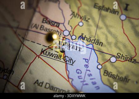 Primo piano di una mappa geografica del Kuwait e del Golfo Persico settentrionale con una spilla d'oro che segna Kuwait City, geopolitica e concetto di viaggio. Alto Foto Stock