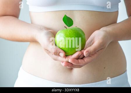 Donna che tiene la mela verde in un concetto di stile di vita sano Foto Stock