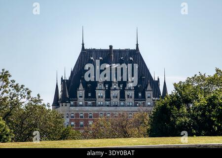 Quebec City, Canada - 23 agosto 2025: Fairmont le Chateau Frontenac, storico hotel in stile castello con tetto scuro ripido e torrette che si innalzano sopra il verde Foto Stock