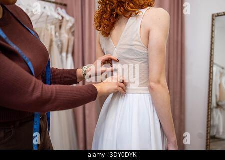 La giovane sposa è stata aiutata nel suo vestito da sposa Foto Stock