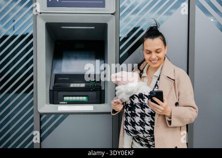 Usando un bancomat in una città Foto Stock