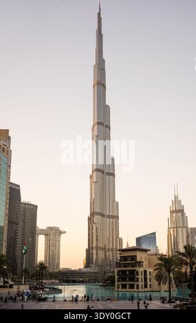 Uno scatto verticale a tutta lunghezza del Burj Khalifa che si innalza in un cielo pallido a Dubai, Emirati Arabi Uniti. L'iconica struttura a più livelli è centrata, fiancheggiata Foto Stock
