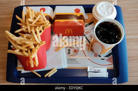 Pasto fast food con hamburger, patatine fritte e cola servito su vassoio all'interno del ristorante McDonalds. Concetto di catena globale di fast food e ristoranti informali Foto Stock