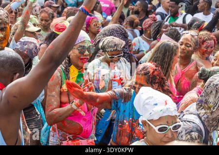 La folla caraibica balla al Carnevale di Notting Hill jouvert Paint party. Londra, Regno Unito, 25 agosto 2024 Foto Stock