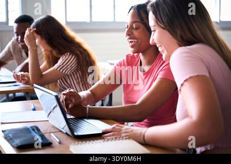 Allegra studentesse che condividono un notebook all'università Foto Stock