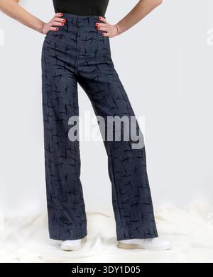 Donna elegante che indossa il denim a vita alta con motivi geometrici e il concetto di studio di moda contemporaneo con corpo nero Foto Stock