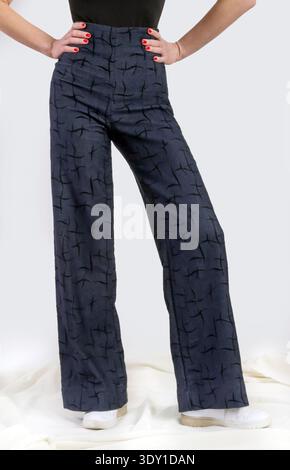 Donna elegante che indossa il denim a vita alta con motivi geometrici e il concetto di studio di moda contemporaneo con corpo nero Foto Stock
