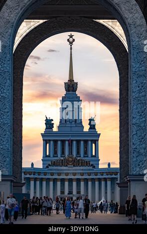 Mosca, Russia - 25 agosto 2025: Padiglione centrale VDNKh incorniciato da un'arcata al tramonto, simbolo di Mosca Foto Stock