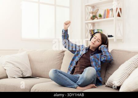 La ragazza ascolta la musica con gli auricolari a casa Foto Stock