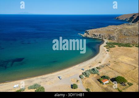 Vista aerea dell'isolata spiaggia di Karvounolakas sull'isola di Limnos, in Grecia, caratterizzata da sabbia dorata, acque turchesi e furgoni di camper parcheggiati in libertà Foto Stock