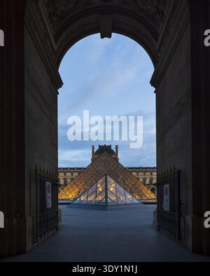 Vista dell'iconica piramide di vetro del Museo del Louvre incorniciata da un arco, Parigi, Francia. Foto Stock