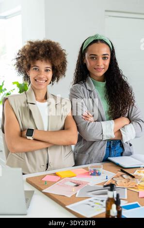 Donne afroamericane che recensiscono il cartone, bottiglie di ambra in studio, in blazer e armi incrociate. Collaborazione, pianificazione, progettazione, prodotto, sviluppo Foto Stock