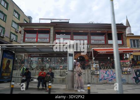 I dettagli nitidi del ristorante Matiate contrastano con la dinamica sfocatura del movimento di pedoni e pendolari in una trafficata fermata dell'autobus di Istanbul. Foto Stock