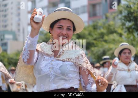 Donna in abbigliamento tradizionale sorridente e danzante durante il vivace carnevale andino Foto Stock