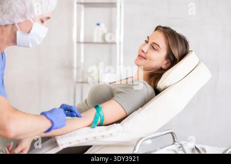 Medico femminile che fa iniezione a una giovane donna sorridente calma in clinica. Foto Stock
