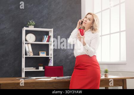 Donna premurosa che si consulta telefonicamente in ufficio Foto Stock