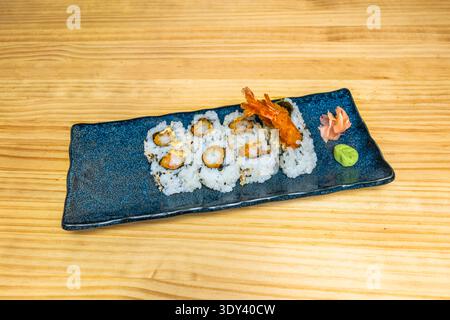Un piatto con diversi uramaki, o sushi roll all'interno, dove il riso è all'esterno e l'alga nori è all'interno, avvolto Foto Stock