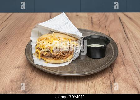 un'immagine semplice ma potente di un'arepa calda divisa a metà, con un pezzo di queso de mano che si fonde all'interno, simboleggiando il calore e la tradizione della casa Foto Stock