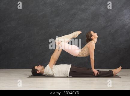 Giovane coppia che pratica acroyoga sul tappeto insieme Foto Stock