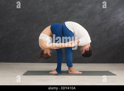 Giovane coppia che pratica yoga insieme in palestra Foto Stock
