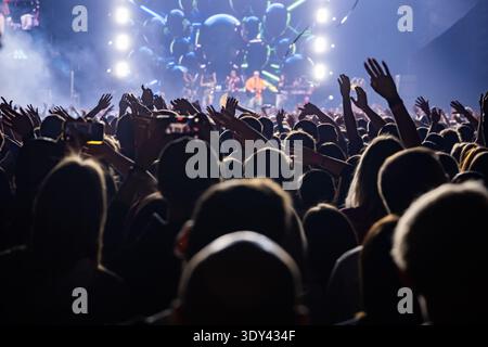 La folla applaude e alza la mano durante un concerto dal vivo di sera Foto Stock