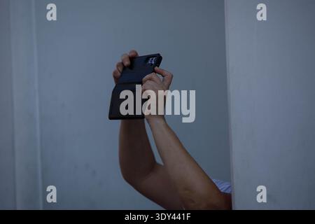 Mani femminili con smartphone che scattano foto nel tempio tailandese, fotografie mobili durante il viaggio, texture della pelle delle mani, primo piano, al Wat Pho. Foto Stock